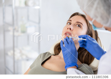 Beautician makeing cosmetic injection in the lips. Woman gets filler injection in her face. Beautician makeing cosmetic injection in the lips. Woman gets filler injection in her face. 111801306