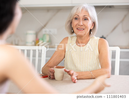 Young woman and elderly woman drinking tea in kitchen 111801403
