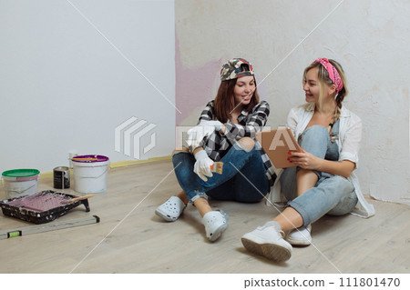 Home interior. Two cute girls designer and painter make repairs in the house.A team of decorators 111801470