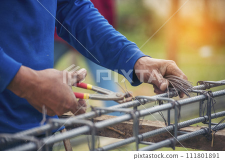 Construction Worker hands using pincer pliers iron wire. Outdoor Worker using wire bending pliers, construction work. Men hands bending cutting steel wire fences bar reinforcement of concrete work 111801891