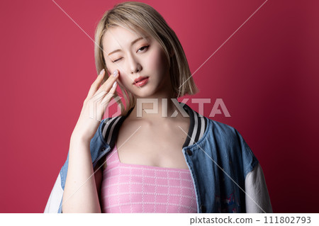 Casual portrait of a young woman photographed against a pink background 111802793
