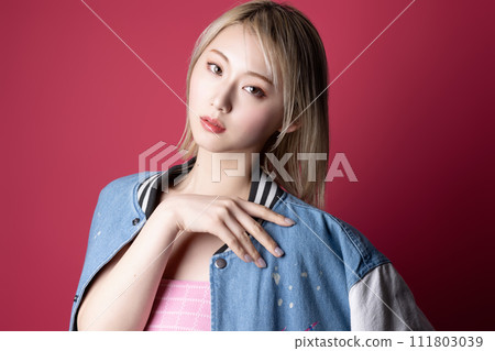 Casual portrait of a young woman photographed against a pink background 111803039