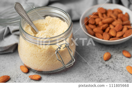 Fresh almond flour in a glass jar and almonds Fresh almond flour in a glass jar and almonds 111805668