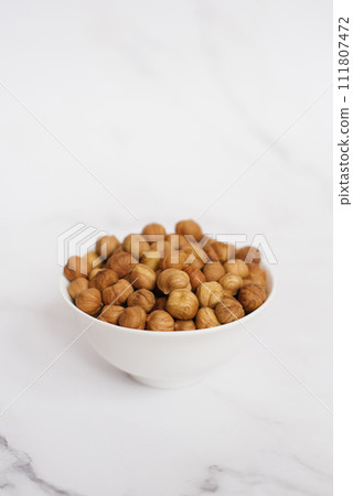Almonds in a white bowl on a marble table Almonds in a white bowl on a marble table 111807472