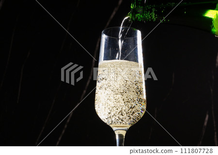 Pour well-chilled champagne (sparkling wine) into a flute glass Pour well-chilled champagne (sparkling wine) into a flute glass 111807728