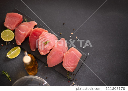 Pieces of Fresh tuna Fish fillet on stone serving board ready to be marinated Pieces of Fresh tuna Fish fillet on stone serving board ready to be marinated 111808178