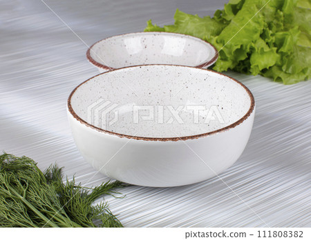 Ceramic clay plate with dark edging on gray background 111808382