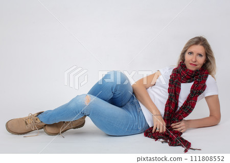 Adult beautiful slender woman in jeans and boots posing while lying in the studio. Adult beautiful slender woman in jeans and boots posing while lying in the studio. 111808552