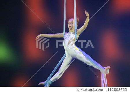 Performance by a circus acrobat artist. Girls perform aerial acrobatic elements on fabric. Performance by a circus acrobat artist. Girls perform aerial acrobatic elements on fabric. 111808763
