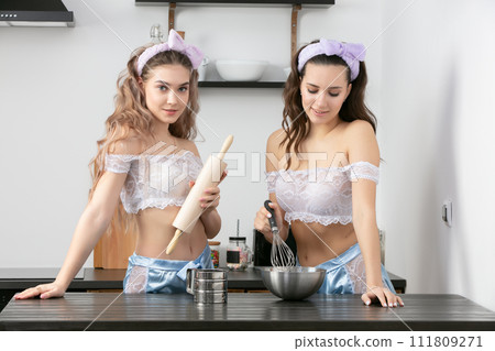 Two beautiful girls in the kitchen. Girlfriends cook food at home in the morning. 111809271