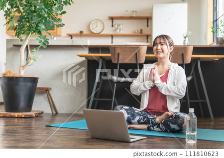 亞洲女性一邊在家裡用筆記本電腦觀看視頻,一邊在網上上瑜伽課 亞洲女性一邊在家裡用筆記本電腦觀看視頻,一邊在網上上瑜伽課 111810623
