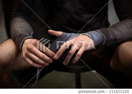 Boxer wrapping hands with boxing handwraps before training 111811220