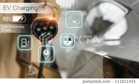 Man holding charging cable at electric charging station. Green energy sustainability concept Man holding charging cable at electric charging station. Green energy sustainability concept 111811435