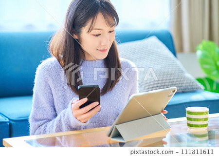A woman comparing the screens of her smartphone and tablet PC A woman comparing the screens of her smartphone and tablet PC 111811611