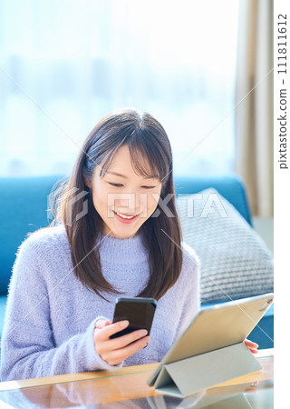 A woman comparing the screens of her smartphone and tablet PC A woman comparing the screens of her smartphone and tablet PC 111811612