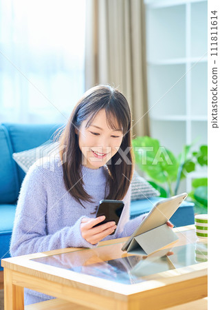 A woman comparing the screens of her smartphone and tablet PC A woman comparing the screens of her smartphone and tablet PC 111811614