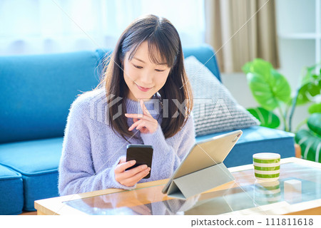 A woman comparing the screens of her smartphone and tablet PC 111811618