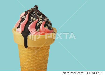 Ice cream. Sweet pink ice cream in a waffle cone poured with chocolate on a turquoise background. Ice cream. Sweet pink ice cream in a waffle cone poured with chocolate on a turquoise background. 111811713