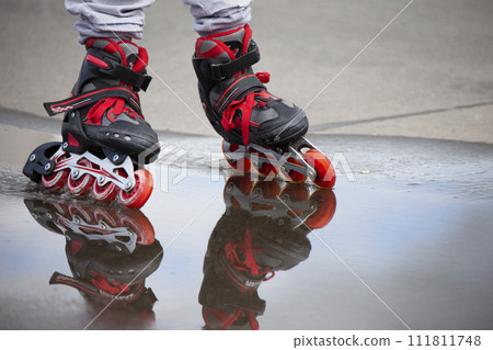 Roller skating. Legs in roller skates ride through a puddle. Roller skating. Legs in roller skates ride through a puddle. 111811748