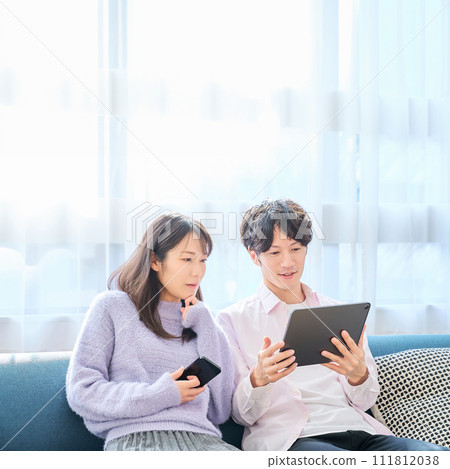 A man and a woman comparing smartphone and tablet PC screens 111812038