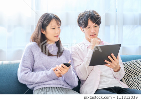 A man and a woman comparing smartphone and tablet PC screens 111812039