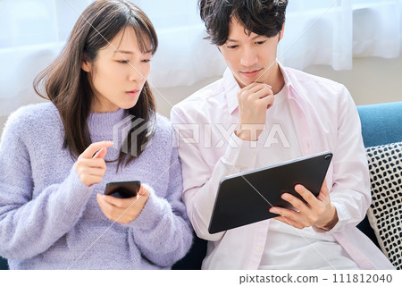 A man and a woman comparing smartphone and tablet PC screens A man and a woman comparing smartphone and tablet PC screens 111812040