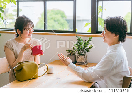 一名女性在咖啡館/餐廳/外出用餐付款時從錢包中取出付款，但一名男性拒絕了。 111813836