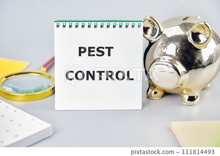 Pest control phrase written on a notebook on a gray background near a calculator, a piggy bank, and stickers. Small Business Concept 111814493