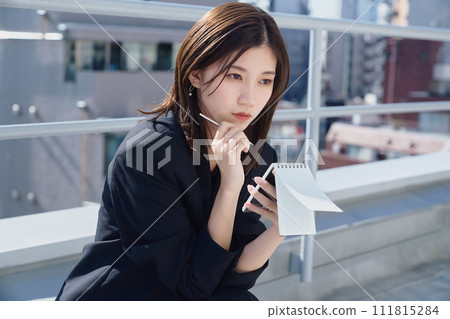 Business woman taking notes on the rooftop Business woman taking notes on the rooftop 111815284