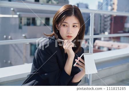 Business woman taking notes on the rooftop Business woman taking notes on the rooftop 111815285