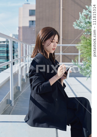 Business woman taking notes on the rooftop Business woman taking notes on the rooftop 111815314