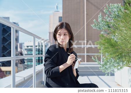 Business woman taking notes on the rooftop Business woman taking notes on the rooftop 111815315