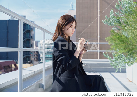 Business woman taking notes on the rooftop Business woman taking notes on the rooftop 111815322