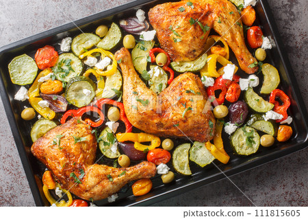 Homemade baked chicken quarters with vegetables and feta cheese close-up on a baking sheet. Horizontal top view 111815605