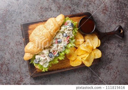 Homemade Healthy Chicken Salad Croissant Sandwich with potato chips closeup on a wooden board. Horizontal top view 111815616
