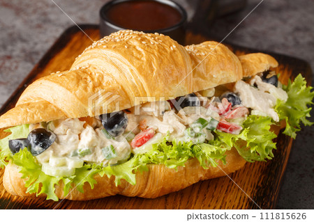 Chicken salad on a flaky butter croissant on a wooden board. Horizontal 111815626