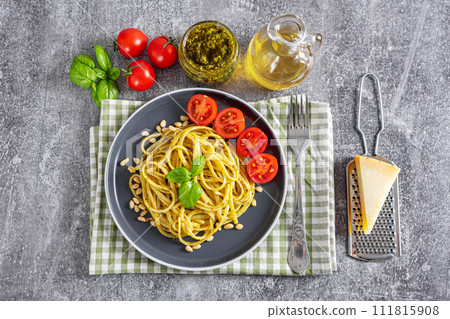 Traditional italian spaghetti pasta pesto with tomato and fresh basil leaves in black bowl, top view Traditional italian spaghetti pasta pesto with tomato and fresh basil leaves in black bowl, top view 111815908