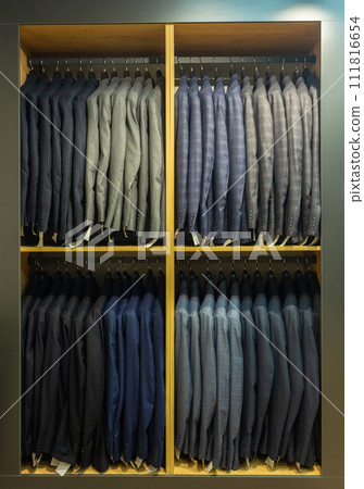 A row of men's suits, jackets hanging on a rack for display. A row of men's suits, jackets hanging on a rack for display. 111816654