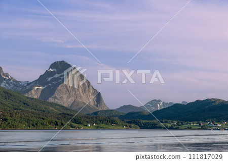 Majestic mountain peak at sunset overlooking calm fjord, with Agskardet houses amidst lush greenery Majestic mountain peak at sunset overlooking calm fjord, with Agskardet houses amidst lush greenery 111817029