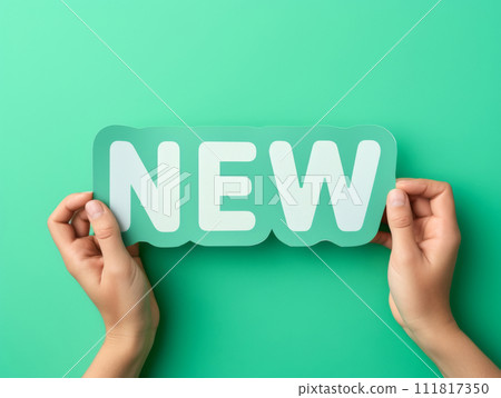 Hands holding new word on turquoise background, top view. Phrase NEW on sticker on green background. Hands holding new word on turquoise background, top view. Phrase NEW on sticker on green background. 111817350