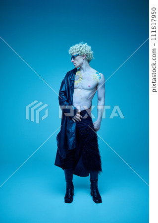 Full length portrait of athletic, young shirtless man posing against blue background in neon-lit studio. Art photography. Full length portrait of athletic, young shirtless man posing against blue background in neon-lit studio. Art photography. 111817950
