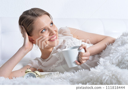 Portrait of young woman relaxing in bed Portrait of young woman relaxing in bed 111818444