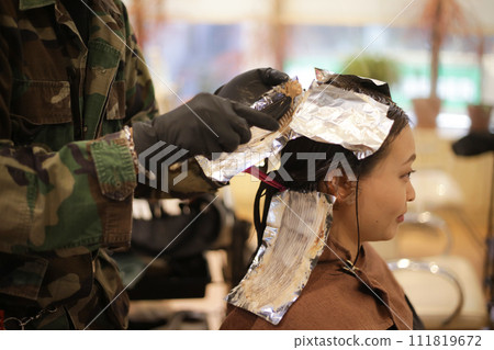 Male hairdresser applying drug to woman's hair 111819672