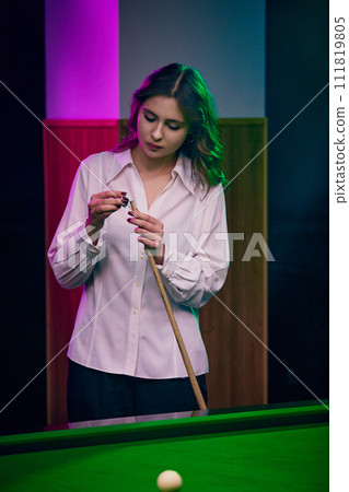 Young woman preparing cue with chalk over billiard table. Poster featuring leisure sports theme. 111819805