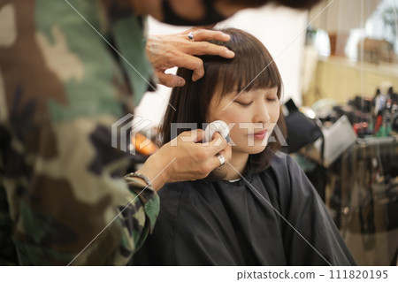 Male beautician applying makeup to a woman 111820195