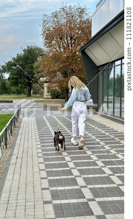 A girl and a dog walking away on a warm autumn day. 111821108