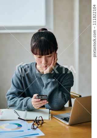 A young woman doing research on her smartphone 111822104
