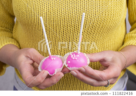 Hands hold two pink sweet candies on a stick. 111822416