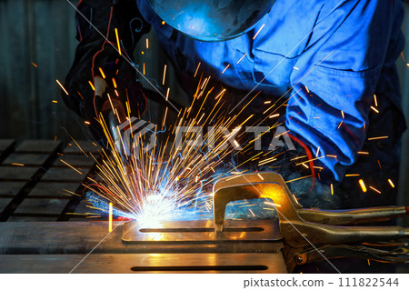 When workers weld using gas argon to steel, sparks are created that result in smoke within factory 111822544