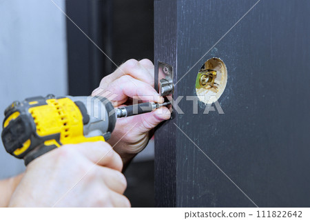 Installing lock handles with screwdriver on room door by carpenter Installing lock handles with screwdriver on room door by carpenter 111822642